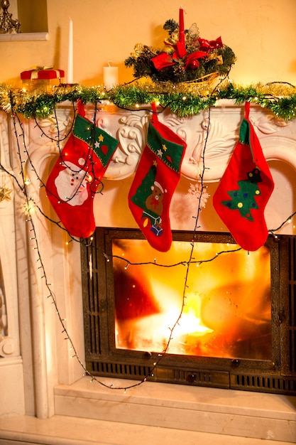 Primo piano interno di tre calze di Natale appese al caminetto decorato