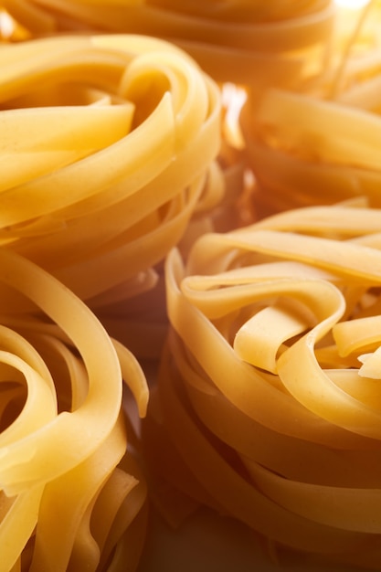 Primo piano italiano del nido della pasta all'uovo. Fettuccine sfondo