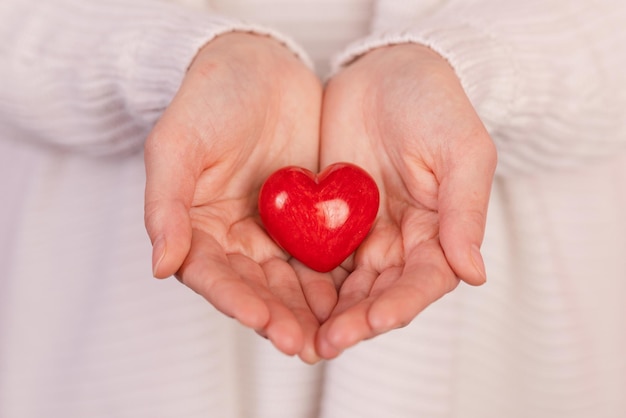 Primo piano mani che tengono il cuore su sfondo rosa concetto di san valentino