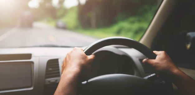 Primo piano mano autista auto su strada con il sole