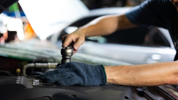 Primo piano mano e chiave Ingegnere meccanico maschio riparazioni e servizio auto in garage Manutenzione auto e servizio auto concetto di garage