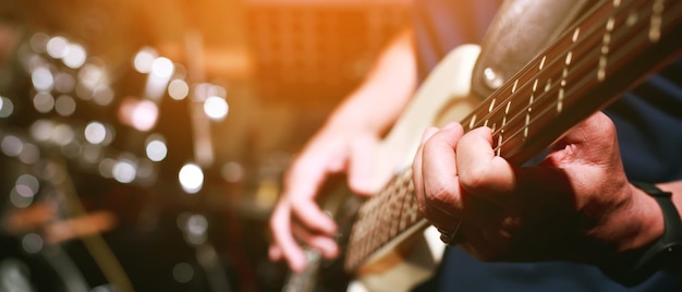 Primo piano mano giovane suonare la chitarra elettrica alla base di prove in studio di registrazione. gruppo musicale rock.