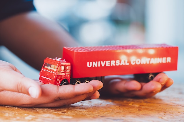 Primo piano mano tenere il contenitore universale camion rosso utilizzando per la logistica e il concetto di business