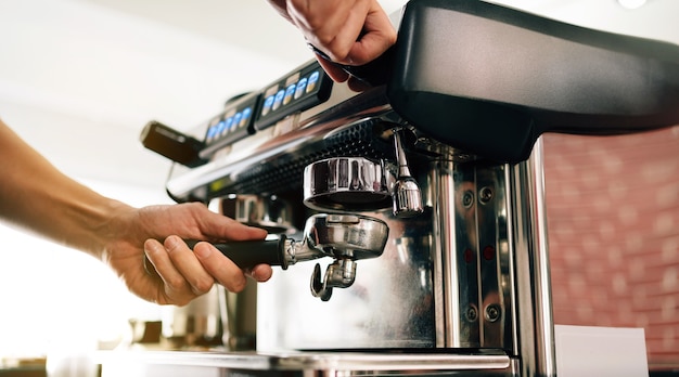 Primo piano maschio barista mano inserisce il filtro metallico nella macchina per il caffè