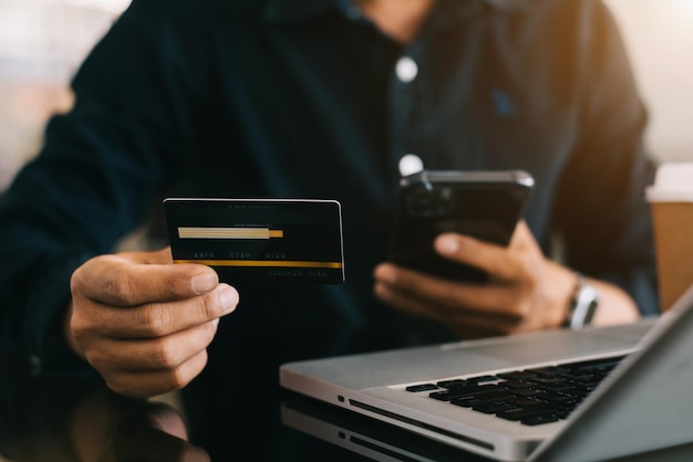 Primo piano maschio che tiene la mano della carta di credito L'uomo d'affari usa i pagamenti online dello smartphone shopping toccando i numeri dei nomi dei telefoni cellulari dello schermo