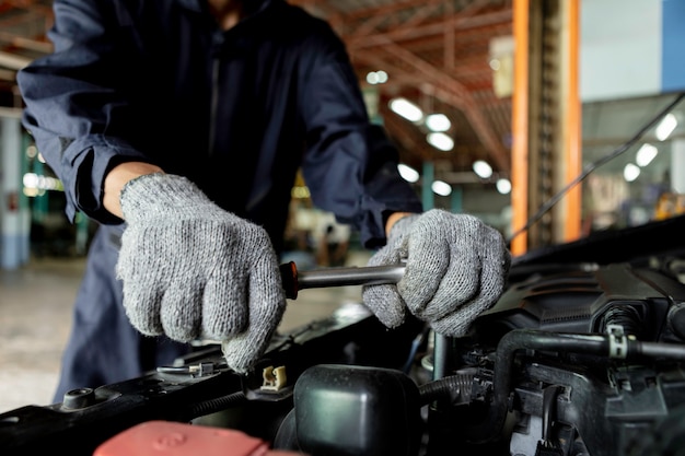 Primo piano, Meccanico automatico Le persone riparano un'auto Usa una chiave inglese e un cacciavite per lavorare. Servizio di riparazione. autentico primo piano.