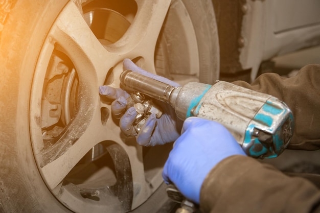 Primo piano Meccanico professionista che cambia la ruota dell'auto nel servizio di riparazione auto Lavoratore automatico che esegue la sostituzione di pneumatici o ruote nel garage della stazione di servizio di riparazione