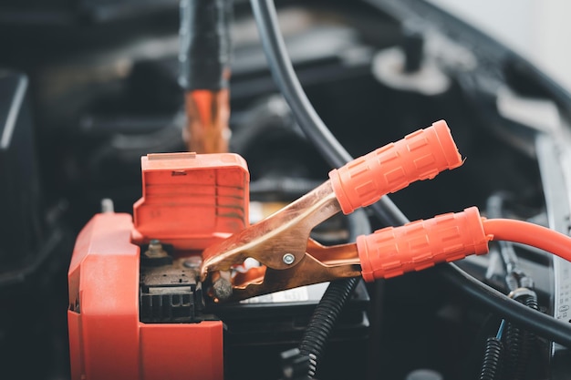 Primo piano Messa a fuoco selettiva del meccanico che attacca i cavi jumper alla batteria di ricarica dell'auto