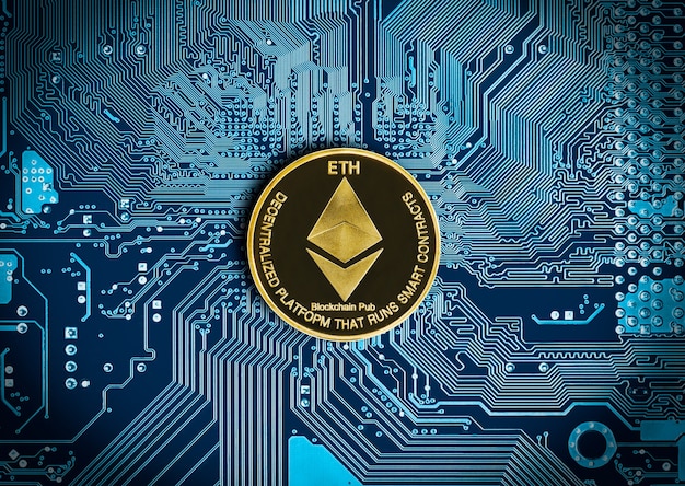 Primo piano moneta ethereum sulla scheda madre del circuito blu dello sfondo del computer