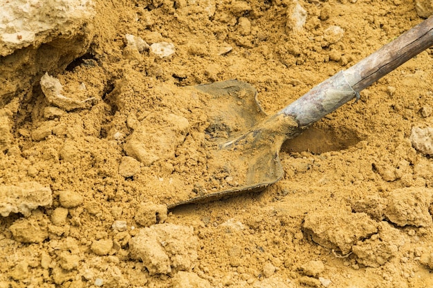 Primo piano pala con sabbia durante i lavori di costruzione. Ambiente di lavoro in cantiere.