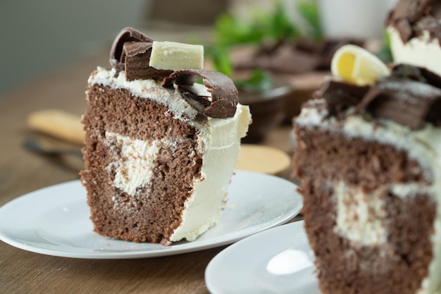 Primo piano pezzo di torta al cioccolato bianco e cioccolato fondente due amori sul tavolo di legno Torta di compleanno e matrimonio