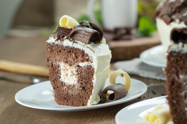 Primo piano pezzo di torta al cioccolato bianco e cioccolato fondente due amori sul tavolo di legno Torta di compleanno e matrimonio
