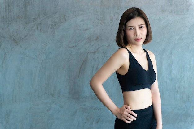 Primo piano ragazza asiatica bella sportiva sul muro della palestraThailandia amore salute Concetto di allenamento donna sottile