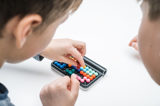 Primo piano retrovisore dei ragazzi gioca gioco da tavolo di strategia educativa con campo nero e palline colorate Terapia con i giochi