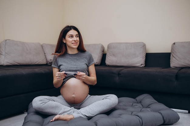 Primo piano ritagliato di una donna incinta in abito verde che mostra un'immagine ad ultrasuoni sulla fotocamera in piedi a casa giovane futura mamma che dimostra la scansione in attesa del primo bambino di gravidanza e concetto di maternità