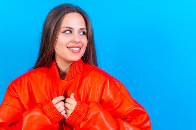 Primo piano ritratto di giovane donna caucasica in giacca a vento rossa isolata su sfondo blu sorridente