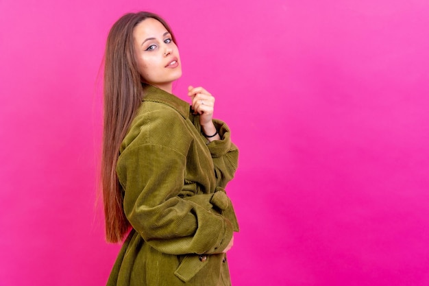 Primo piano ritratto di giovane donna caucasica in trench verde isolato su sfondo rosa sorridente