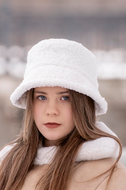 Primo piano ritratto di giovane donna in panama di pelliccia bianca e cappotto di pelle di pecora beige in inverno all'aperto Capispalla giovanile alla moda