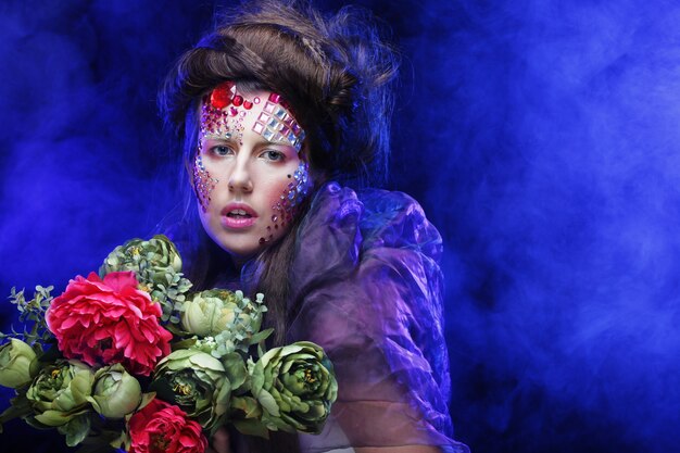 Primo piano Ritratto di giovane donna in un'immagine creativa con grandi fiori.