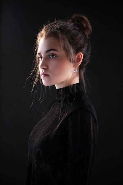 Primo piano ritratto di profilo di una giovane donna indossare valigia nera su sfondo nero