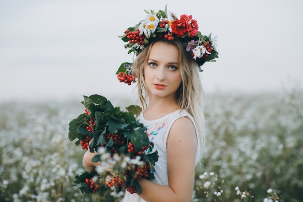 Primo piano Ritratto di una ragazza bionda con gli occhi azzurri con una corona di fiori in testa