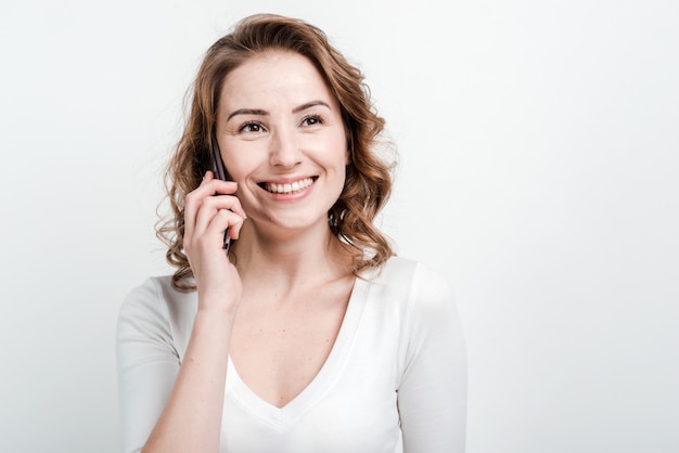 Primo piano, sorridente donna parla al telefono.