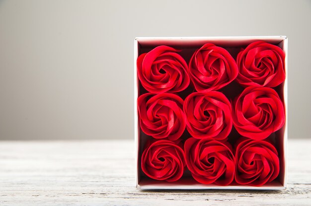 Primo piano strutturato rosso delle rose. Festa della donna, festa della mamma, rose rosse su un fondo di legno bianco.