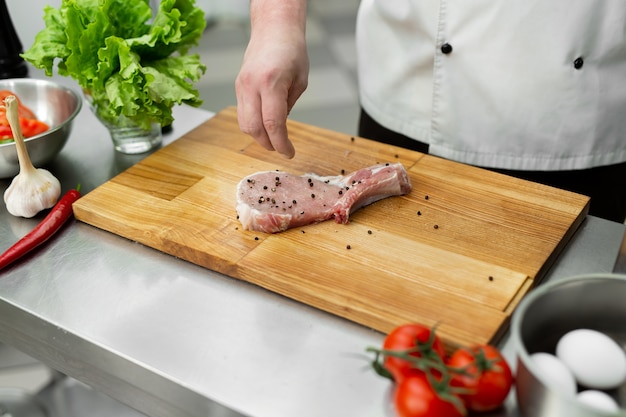 Primo piano su chef infarcendo bistecca di manzo crudo