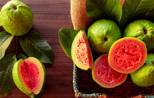 Primo piano su guaiava rossa affettata con la foglia verde sulla tavola di legno rustica