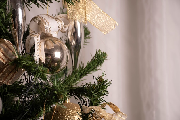 Primo piano su ornamenti appesi da sfondo fantasia albero di Natale per il ritratto di cartolina di Natale con palline d'oro e sfondo paesaggio tenda bianca
