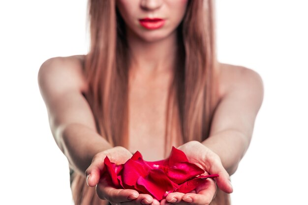 Primo piano su petali di rosa nelle mani di una giovane donna attraente