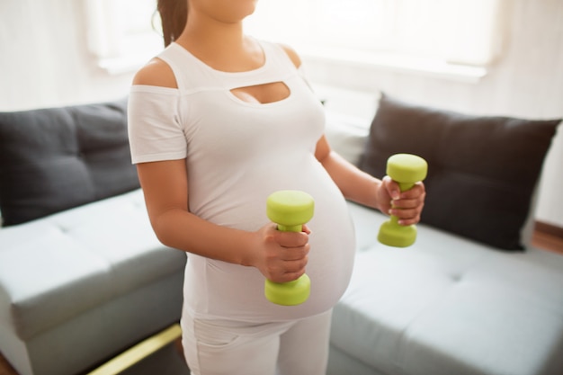 Primo piano su un manubrio. Donna incinta con manubri. Vita sportiva attiva, benessere.