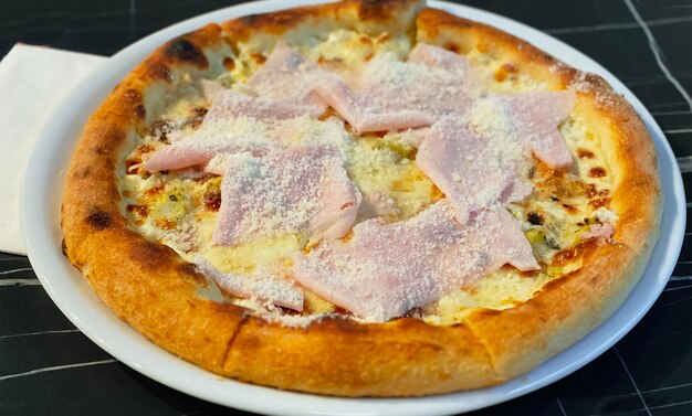 Primo piano su un tavolo da ristorante pizza con prosciutto cotto e taleggio. Concetto di cibo.