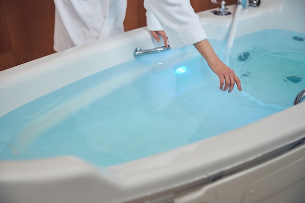 Primo piano su una donna caucasica che tocca la superficie dell'acqua con una mano