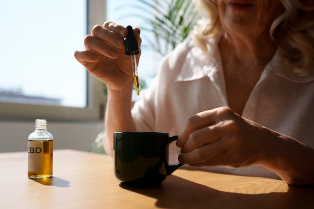 Primo piano su una donna che mette l'olio di CBD nella bevanda