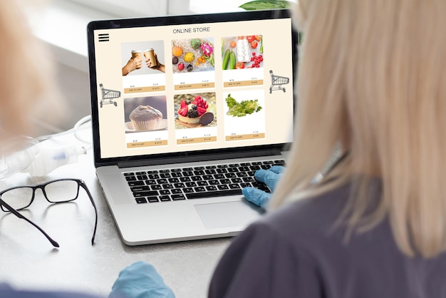 Primo piano su una donna seduta e che ordina cibo online sul computer portatile nella pagina web della funzione Aggiungi al carrello.