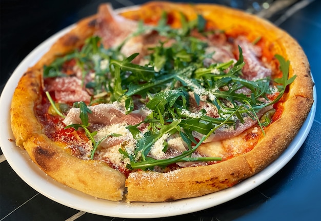 Primo piano su una pizza da tavolo ristorante con prosciutto, rucola e parmigiano. Concetto di cibo.