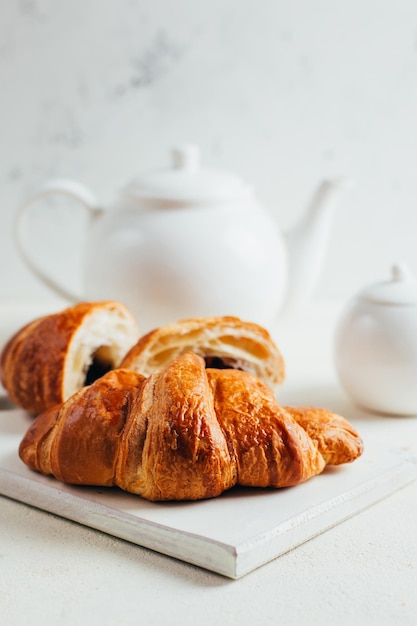 Primo piano sui croissant sullo sfondo di una teiera bianca su sfondo bianco