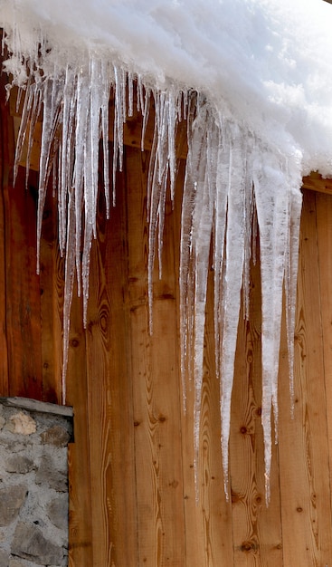 Primo piano sui ghiaccioli davanti alla parete di legno di uno chalet