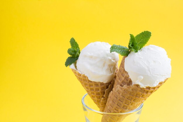Primo piano sul gelato alla vaniglia in un cono di cialda sullo sfondo giallo. Copia spazio.