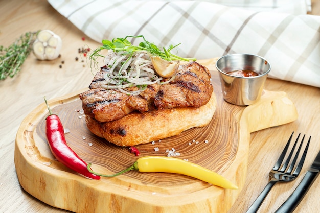 Primo piano sul gustoso collo di maiale alla griglia servito su pane pita con cipolla, microgreen e peperoncino.