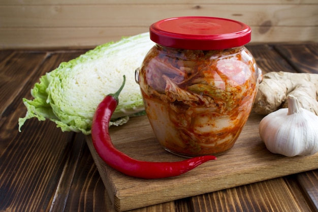 Primo piano sul kimchi nel barattolo di vetro e gli ingredienti sul tagliere
