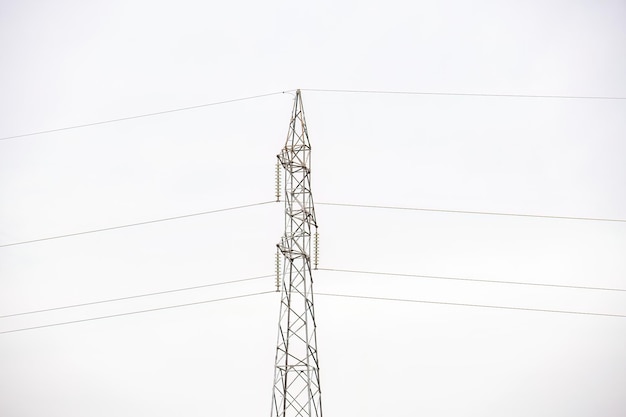 primo piano sul palo della linea di trasmissione di energia elettrica con il cielo bianco sullo sfondo