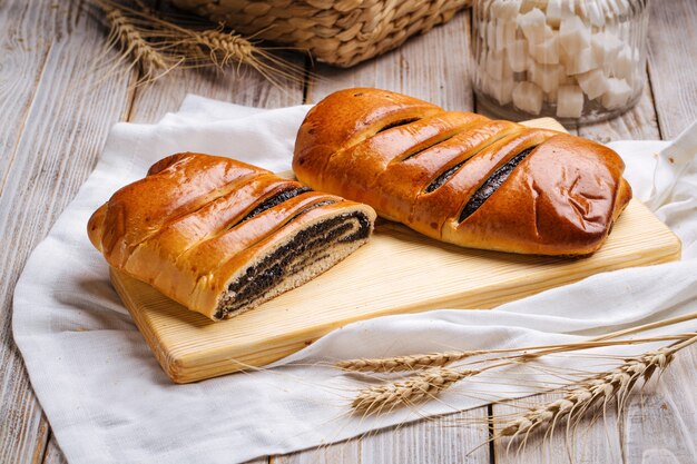 Primo piano sul panino del seme di papavero tagliato sulla tavola di legno