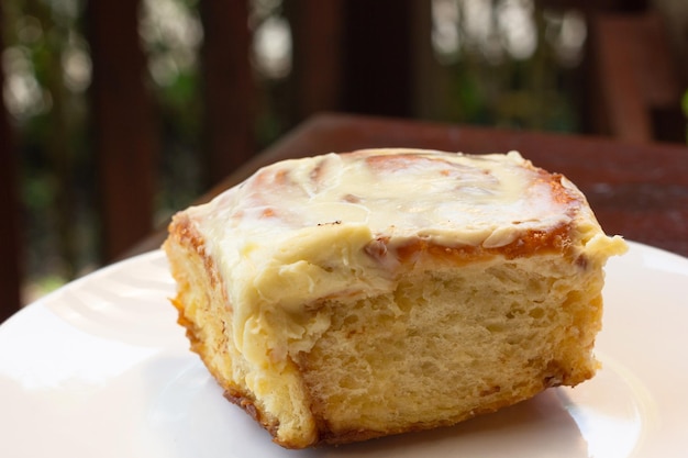 Primo piano sul rotolo di cannella a velo sulla piastra bianca. Dessert dolce al panificio