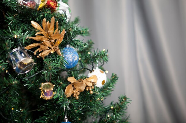 Primo piano sull'albero di natale con ghirlande e decorazioni in casa. Albero verde decorativo e festoso