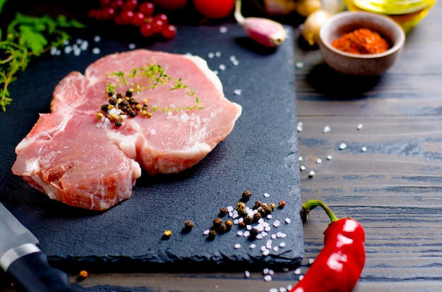 Primo piano sulla bistecca cruda di carne di maiale con vari ingredienti