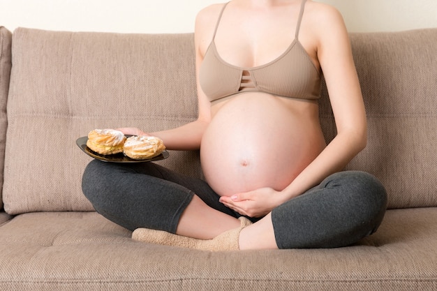 Primo piano sulla donna incinta che mangia torte