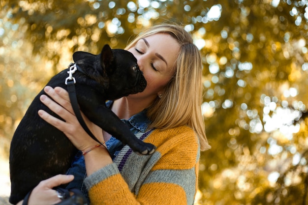 Primo piano sulla giovane donna felice con il cane all'aperto in autunno