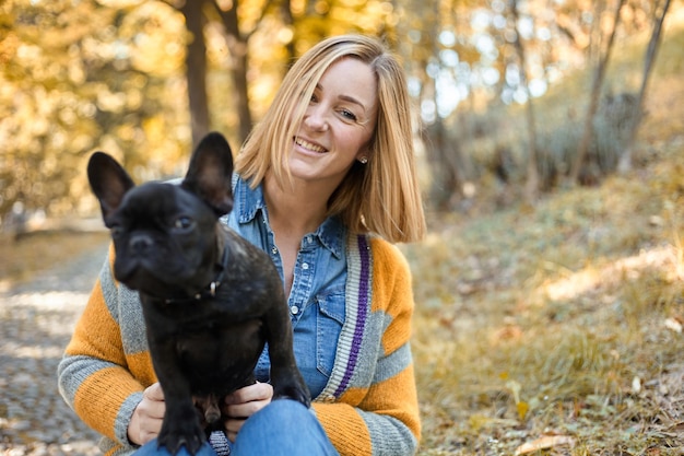 Primo piano sulla giovane donna felice con il cane all'aperto in autunno